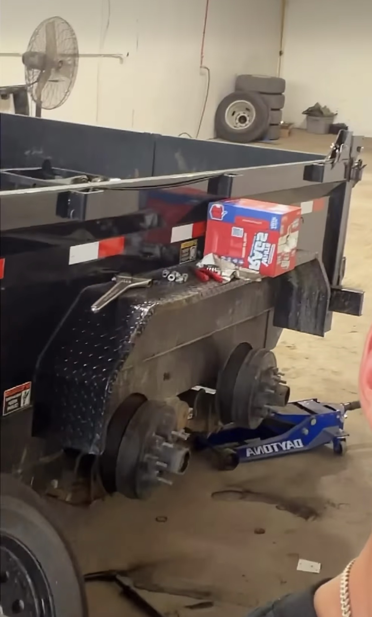 Dump trailer with both wheels removed and brake hubs exposed during a bearing repair