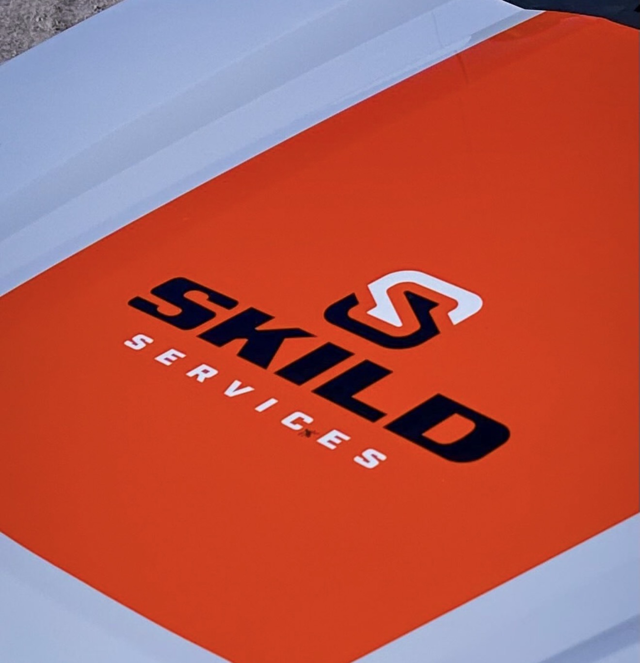 SKILD Services logo on the orange striped hood of the mobile service truck
